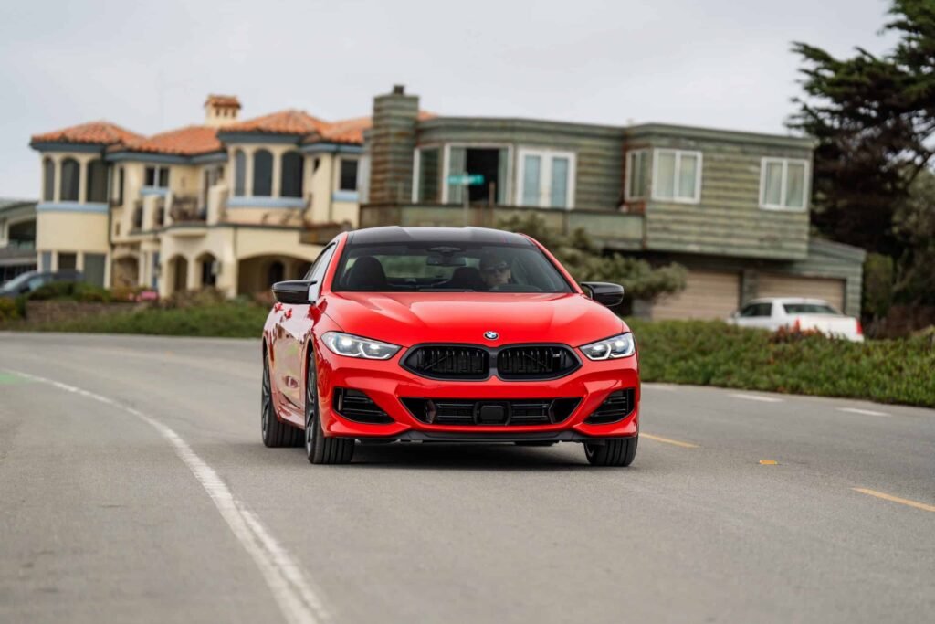 2026 BMW M850I HERITATE EDITION BRIGHT RED driving in Pebble Beach